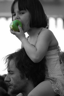 Jeune fille mangeant une pomme sur les épaules de son père Enfant dégustant un fruit